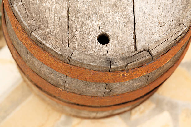 Close-up of the edge of a wooden wine barrel,low depth of field, with more wine barrels in the background.