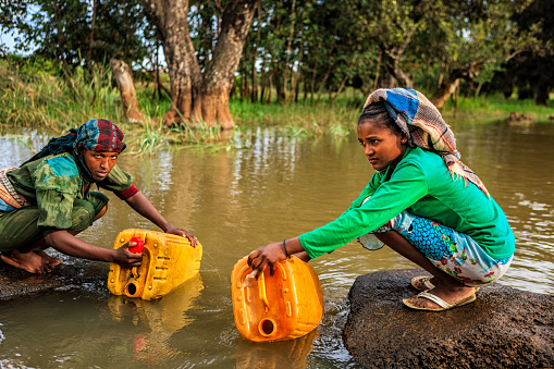African women are taking water from the river, African women and children often walk long distances to bring back jugs of water that they carry on their back.http://bhphoto.pl/IS/ethiopia_380.jpg