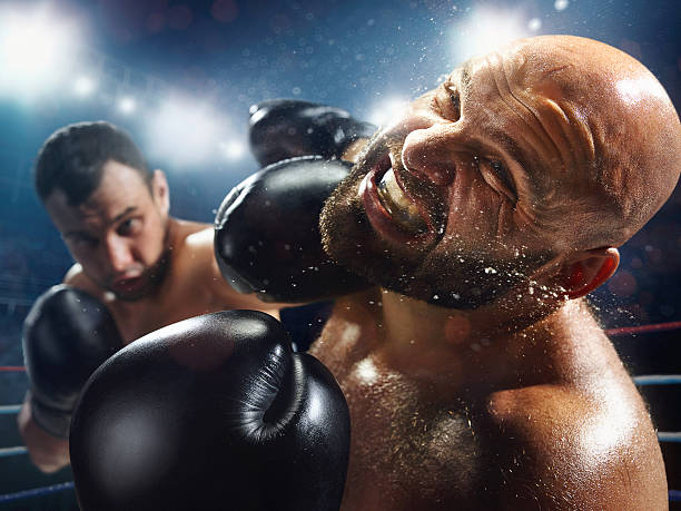 Boxing: Extremely powerful punch The action takes place on a professional ring with high weight sportsmen.  A sportsman in yellow shorts kicks off the soul of the opponent. All wear unbranded cloth and sport equipment boxing stock pictures, royalty-free photos & images