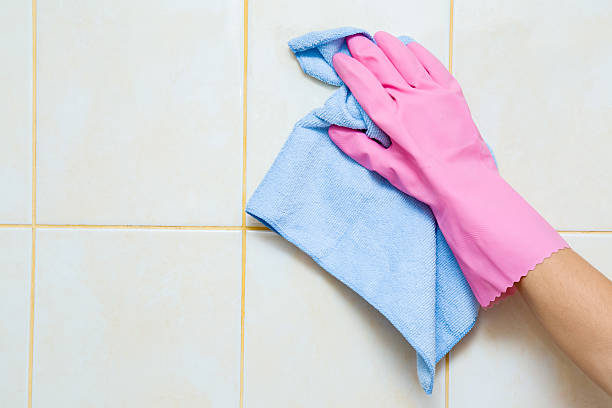 istock Hand in pink protective glove cleaning tiles with rag. 626816612