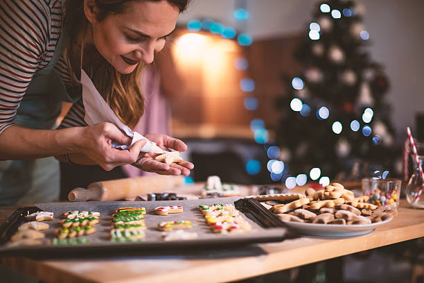 Making Gingerbread cookies for Christmas Young woman decorating a Gingerbread cookies for Christmas. Christmas Tree Cookie stock pictures, royalty-free photos & images