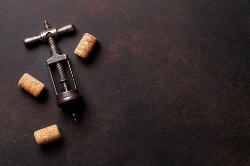 Vintage corkscrew and wine corks on stone table. Top view with copy space