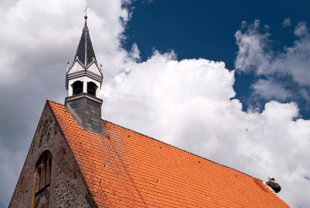 A rustic wooden Orthodox church spire stretches upwards against a cloudy sky, to the heavens, showcasing detailed craftsmanship.