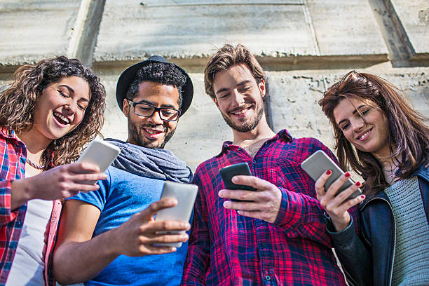 istock Low angle view of happy friends using smart phones 626830602