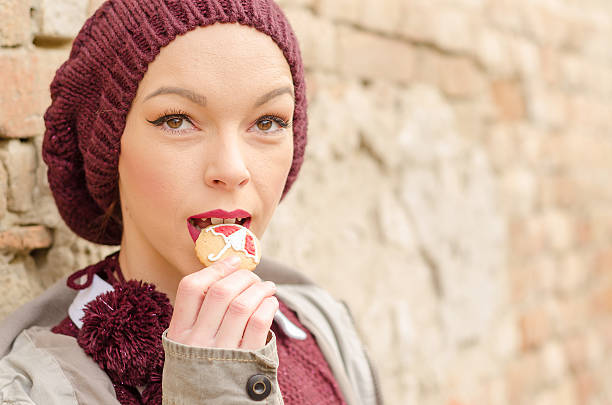 istock woman leaning on an old brick wall eating a cookie 626838786