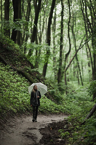 istock Young girl walking through a rainy forest with umbrella. 626839078
