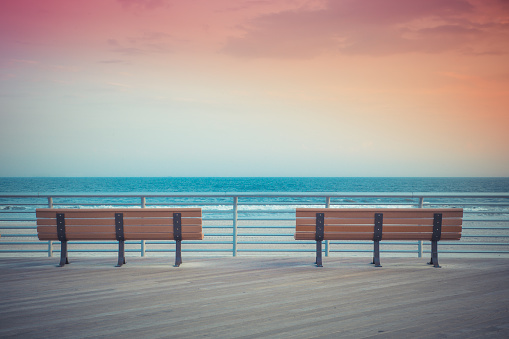 pastel toned beach boardwalk benches with ocean and sunset