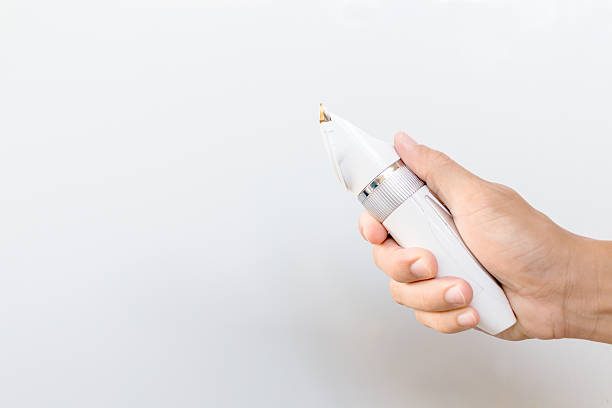 istock Hand holding hair clippers on grey background 626840254
