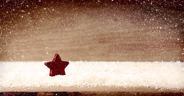 istock Christmas wooden background with star and snowfall. 626841244