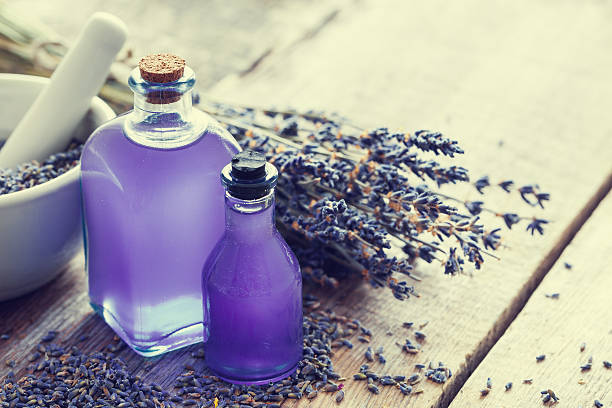 deux bouteilles d’huile essentielle, de mortier et de fleurs de lavande. - lavender spa treatment health spa flower photos et images de collection