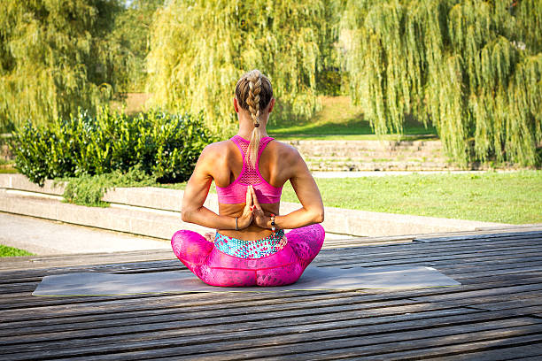 junge frau macht yoga mudras und posiert in einem park. - mudras stock-fotos und bilder