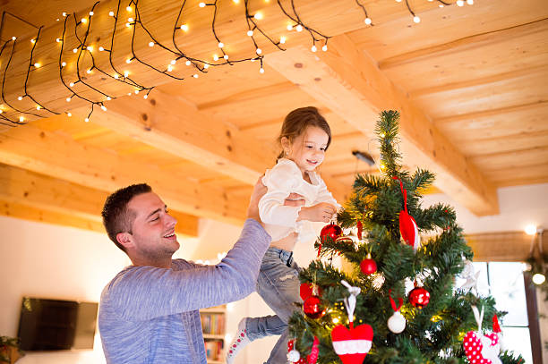 istock Young father with daugter decorating Christmas tree together. 626844116