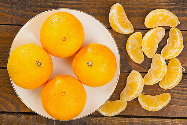 istock juicy Spanish mandarins on plate on wooden background 626844644