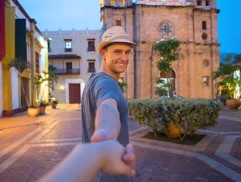 Couple in love holding hands and traveling together in Cartagena and man leading the way
