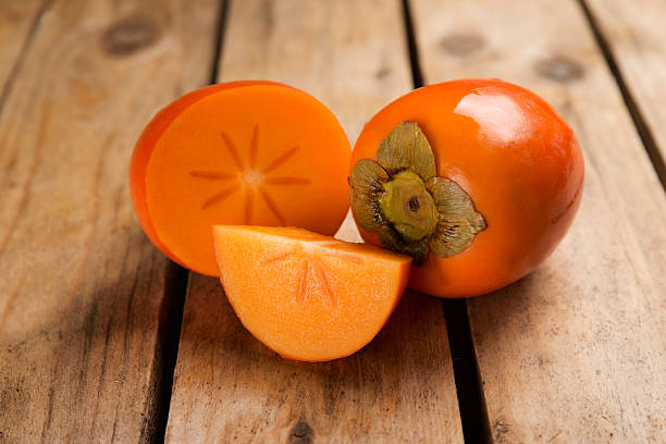 details persimmon fruit on rough wooden table - persimmon imagens e fotografias de stock