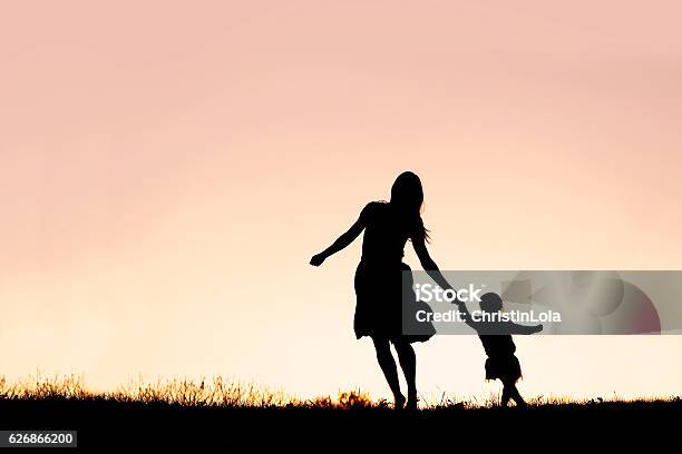 Silueta De Madre Y Ni Hija Corriendo Y Bailando Al Atardecer Foto de stock y más banco de imágenes de Madre