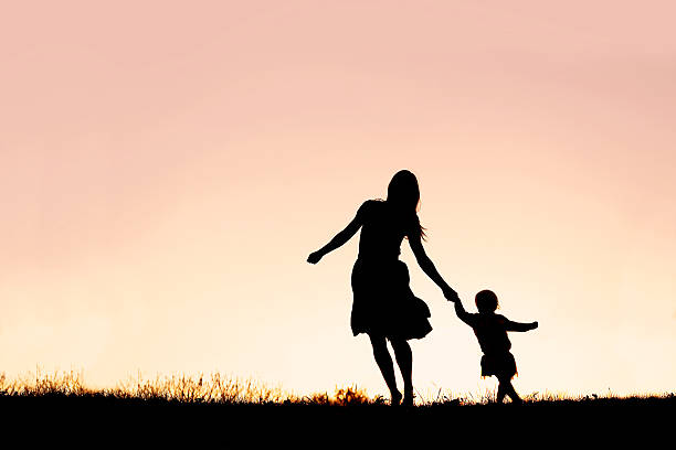 silhouette di madre e figlia che corrono e ballano al tramonto - christin foto e immagini stock