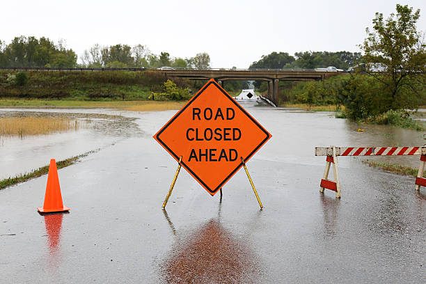 Road Closed Ahead Sign Over Rain Flooded Street stock photo