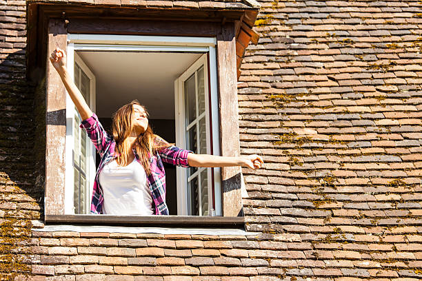 istock Young woman waking up and stretching on rooftop window 626868068