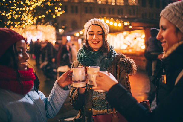 enjoying mulled wine on christmas market - friendship women group of people 20s imagens e fotografias de stock