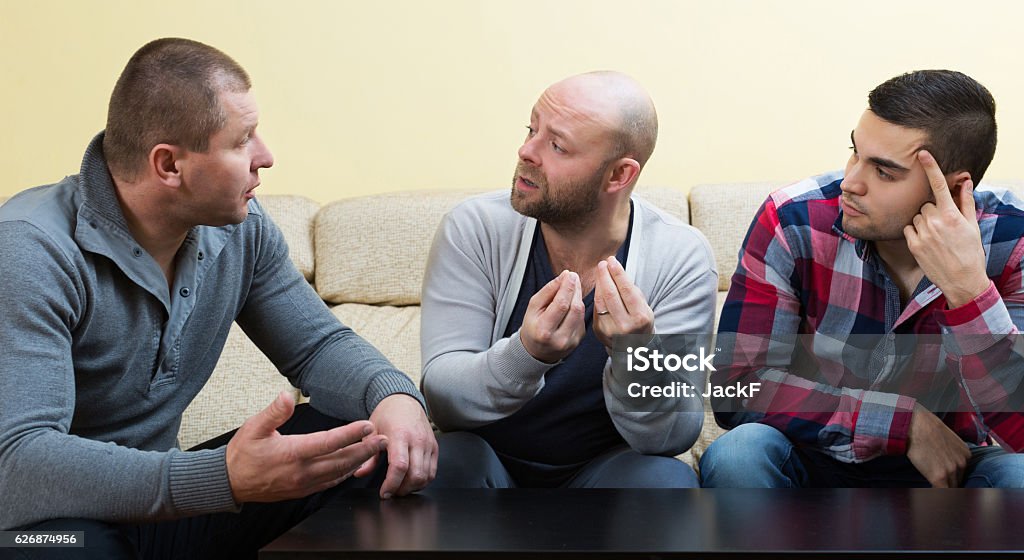 Three males  at home Three unhappy males having a serious conversation at home Men Stock Photo