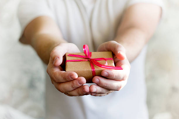 istock podaroks red ribbon in the men's hands 626875184