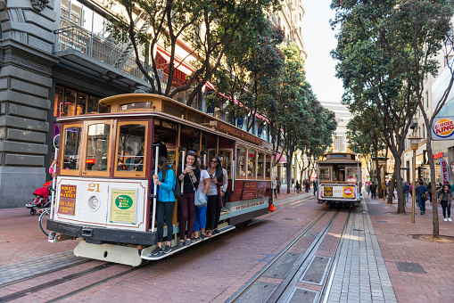 San Francisco, USA - October 23, 2016: Two iconic cable cars photographed in duty on Powell Street in San Francisco, California. The one on the left is fully occupied, mostly with tourists and going uphill. The other one is waiting for its next service. Cable cars are one of the symbols of San Francisco.