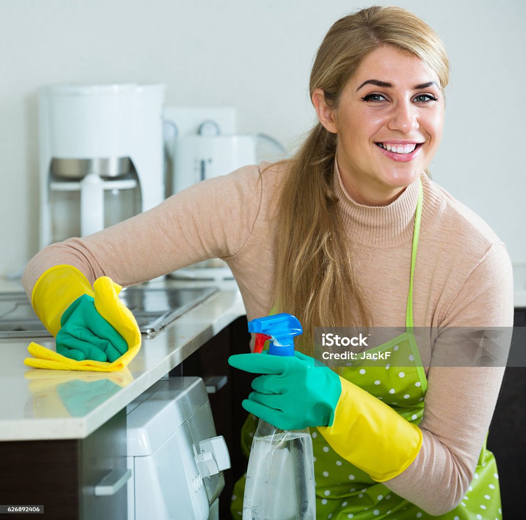 Blonde maid cleaning in domestic kitchen happy european blonde maid cleaning in domestic kitchen with sprayer 30-39 Years Stock Photo