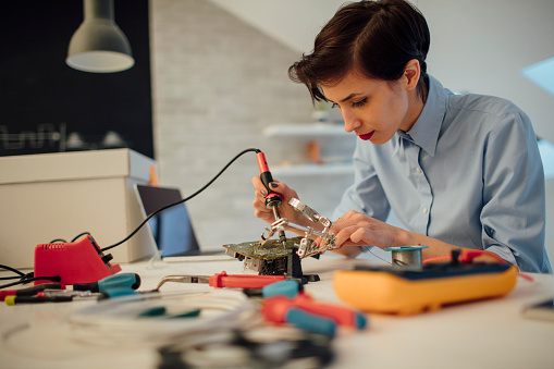 Una mujer de soldadura en placa de circuito tecnología en su oficina. photo