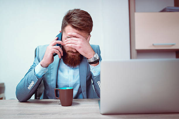 worried and exhausted businessman talking on phone in his office - isolated businessman sadness business person imagens e fotografias de stock