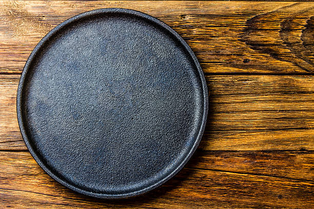 istock Empty rustic black cast iron plate over old wooden background 626917278