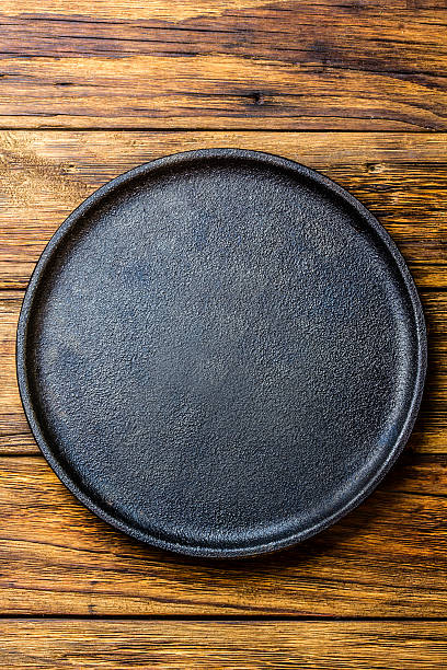 istock Empty rustic black cast iron plate over old wooden background 626931624