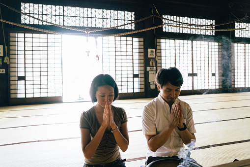 Japanese couple praying in a buddhist temple in Kyoto, Japan