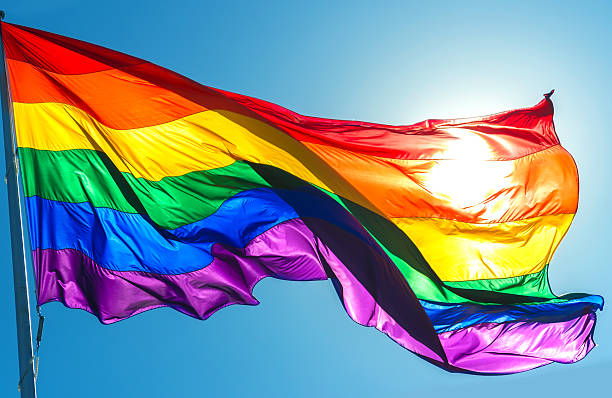 Rainbow flag on the blue sky background stock photo