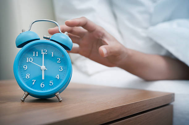 Early morning. Woman hand reaching out bed for retro alarm clock. Early morning. alarm clock snooze stock pictures, royalty-free photos & images