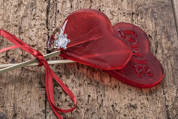 istock Diamond ring and heart shaped candies on wooden surface 626953146