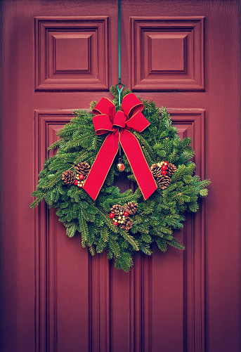 Christmas wreath hanging on a red wooden door. Vintage filter effects.