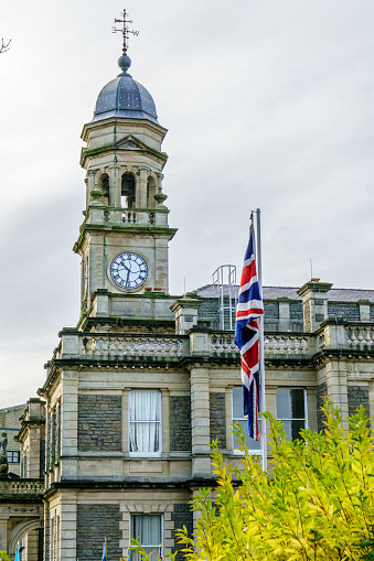 Llanelli, UK - November 13, 2016: Commemorating the military on Armistice Day. Union Jack flying above the ceremony held in the grounds of Llanelli Town Hall