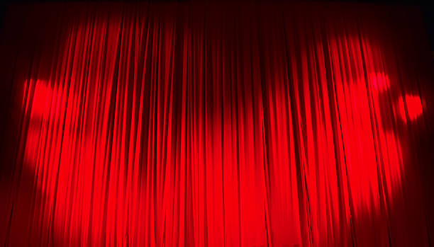 istock Red closed curtain with light spots in a theater 626962680