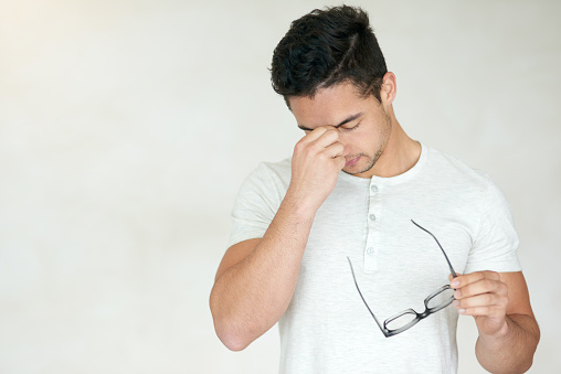 Studio shot of a young man looking stressed against a light background