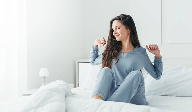 Girl waking up and stretching Beautiful woman waking up in her bed in the bedroom, she is stretching and smiling waking up stock pictures, royalty-free photos & images