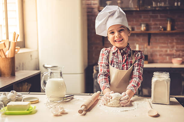 petite fille faire cuire au four - rolling dough pastry apron photos et images de collection