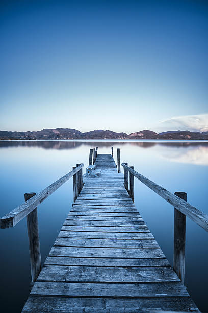 istock Wooden pier jetty  blue lake sunset and sky reflection on 626995904
