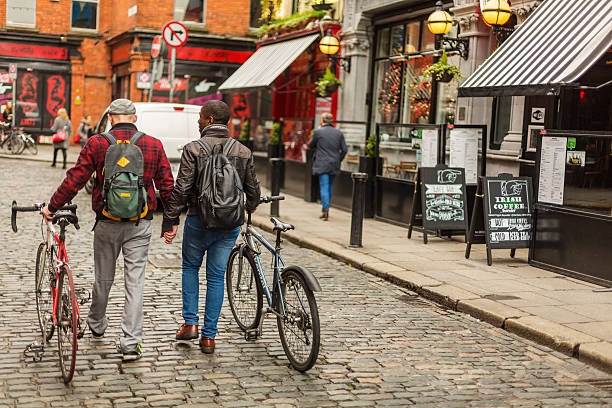 pareja gay de raza mixta con bicicletas en la ciudad - dublin ireland urban road people real people fotografías e imágenes de stock