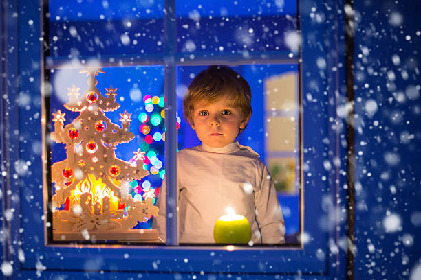 istock Little kid boy standing by window at Christmas with snow 627003046