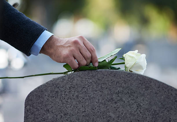 Paying his respects… Cropped shot of a man placing a white rose on a grave tombstone stock pictures, royalty-free photos & images