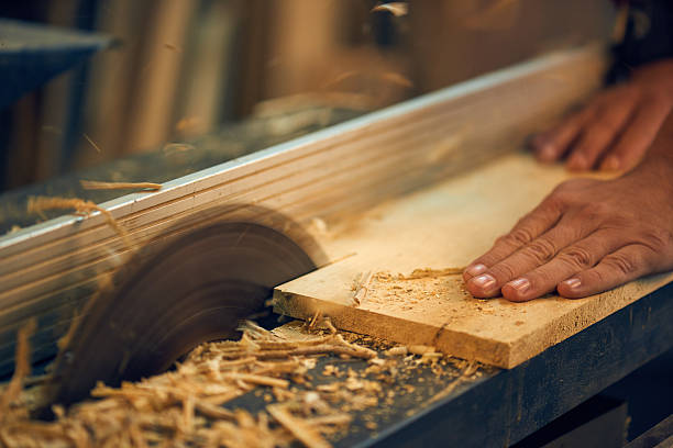 carpenter using circular saw in workshop - kesmek stok fotoğraflar ve resimler