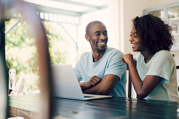 Cheerful couple using laptop at home