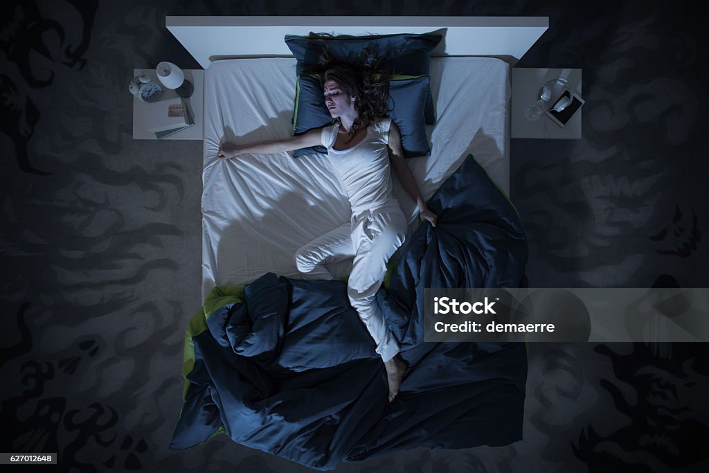 insomnia and nightmare in bed at night Nervous woman suffering from insomnia and lying in bed late at night, she is awake and restless, top view Sleeping Stock Photo