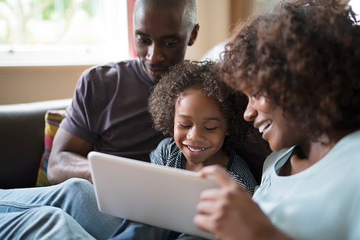 Familia alegre usando tableta digital en sofá photo